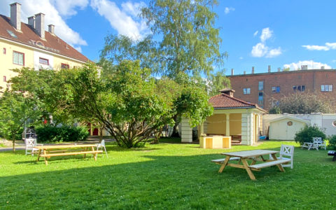 Bord, paviljong, grønt gress, og bygninger i en bakgård.